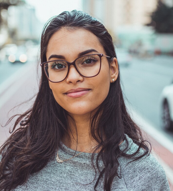 A young woman with looks at the camera with pride. (Image courtesy of Pexels).