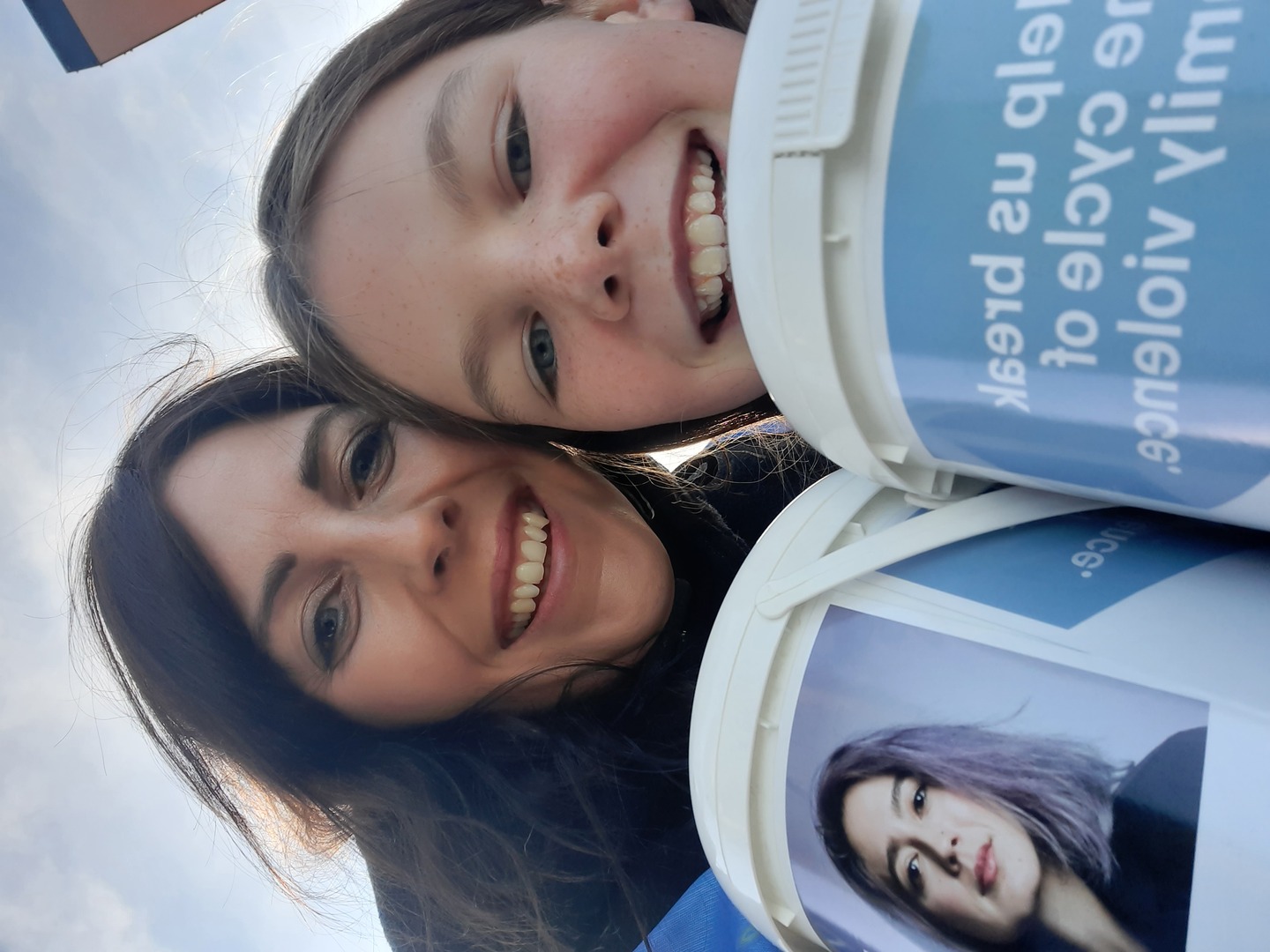 A mother and daughter wearing Aviva vests hold Aviva collection buckets for a selfie.