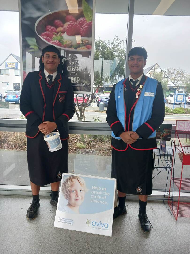 Two teen Pasifika boys collecting bucket donations for Aviva in blue vests.