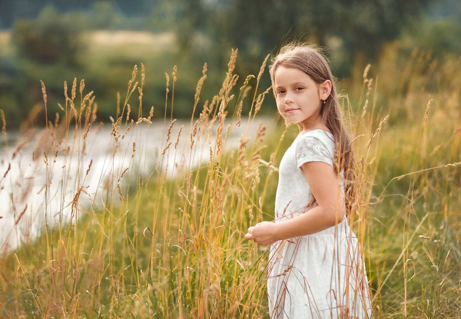 a young girl stands in a field looking at the camera